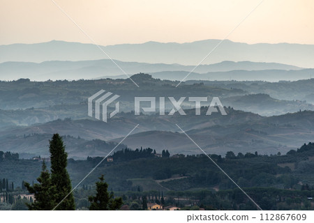 Typical Tuscan landscape with hills and cypresses in the very early morning near Montaione 112867609