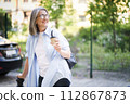 A woman is walking down a street, clutching a cup of coffee in her hand. 112867873
