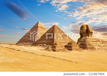 The Sphinx of Giza next to the Pyramids of Egypt and its companions in the sands of Giza desert, Egypt 112867904