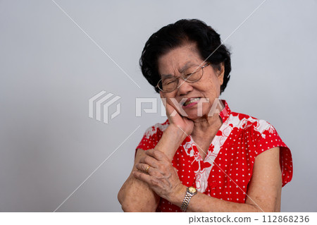 Asia old senior woman suffering from severe toothache, holding her cheek and suffering strong dental pain on white background, tooth decay, tooth sensitivity, oral health care concept. Asia old senior woman suffering from severe toothache, holding her cheek and suffering strong dental pain on white background, tooth decay, tooth sensitivity, oral health care concept. 112868236