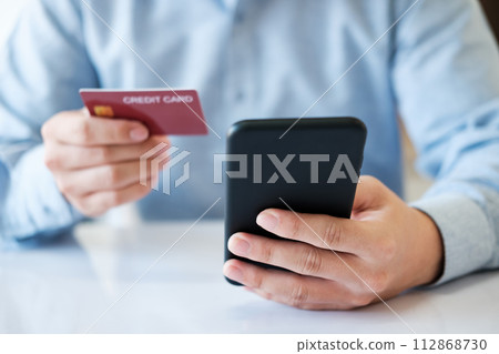 A man is using his phone to pay for a credit card A man is using his phone to pay for a credit card 112868730