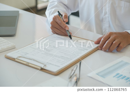 Hands of a businessman about to sign a business contract Hands of a businessman about to sign a business contract 112868765