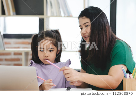 A woman is helping a young girl with her homework A woman is helping a young girl with her homework 112868870