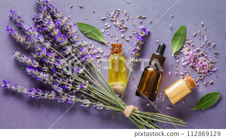 Lavender flowers and herbal essential oil on purple background. Relaxation, anti-stress. Lavender flowers and herbal essential oil on purple background. Relaxation, anti-stress. 112869129
