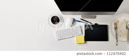 modern white office desk with black screen computer A cup of coffee, a notebook, a pen, a plate of food that has been eaten. top view with copy space, lay flat modern white office desk with black screen computer A cup of coffee, a notebook, a pen, a plate of food that has been eaten. top view with copy space, lay flat 112870402