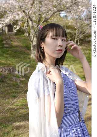 Young woman posing in a park with cherry blossoms blooming 112871224