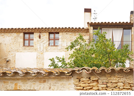 Coast of the Costa Brava. Catalonia. Old village in Spain. Charming old streets. Typical village with beautiful stone houses. Lemon tree ripening in the garden 112872655