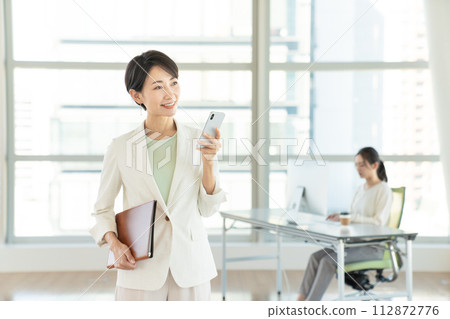 Business woman with a smartphone in the office Business woman with a smartphone in the office 112872776