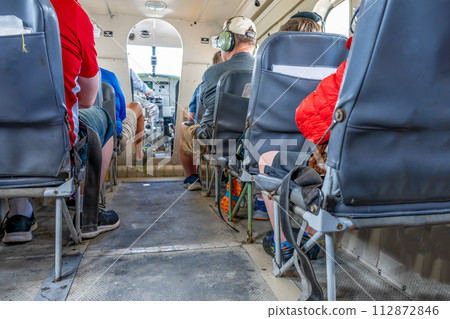 Selective focus floor level view inside a small private tour plane with passengers.  112872846