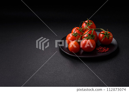 Fresh red cherry tomatoes on a branch on a dark concrete background 112873074