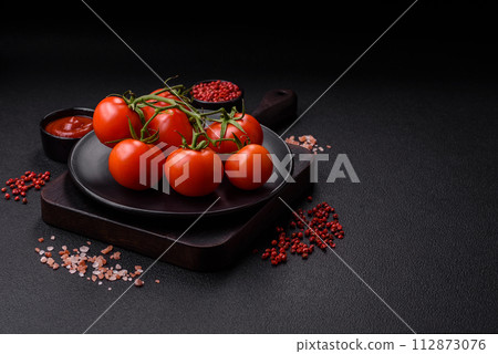 Fresh red cherry tomatoes on a branch on a dark concrete background 112873076