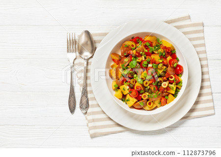 spanish potato salad with chorizo in white bowl 112873796