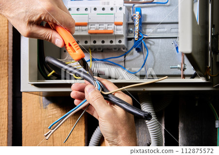 Connecting 3 phase, 4 wire power cable to electrical panel, removing top PVC covering. 112875572