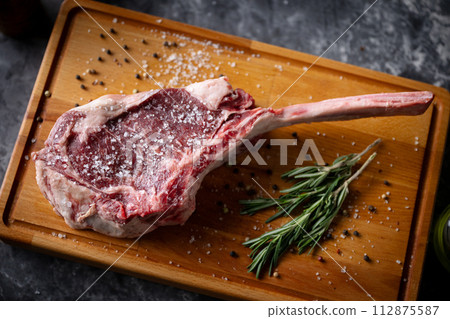 fresh tomahawk steak on rustic board 112875587