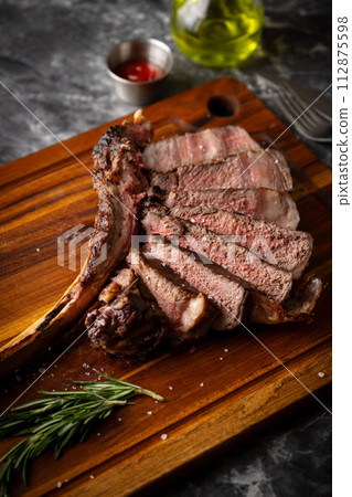 sliced tomahawk steak on wooden board sliced tomahawk steak on wooden board 112875598