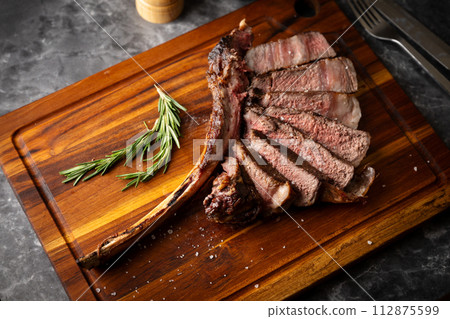 sliced tomahawk steak on wooden board sliced tomahawk steak on wooden board 112875599