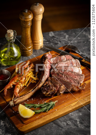 tomahawk steak and shrimps in sunset lighting tomahawk steak and shrimps in sunset lighting 112875604