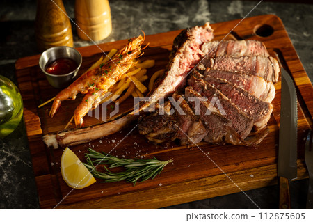tomahawk steak and shrimps in sunset lighting 112875605