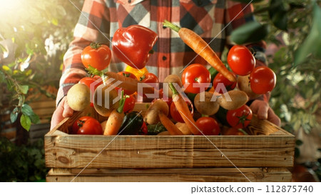 Closeup of Farmer Holding Wooden Crate with Flying Vegetable. 112875740