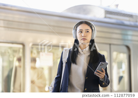 戴著耳機走在月台上的女高中生，與京王電鐵合作拍攝。 112877059