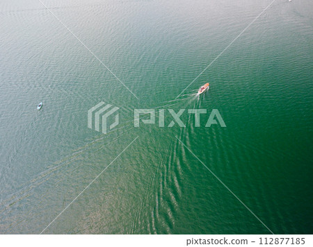 Aerial view of a white speed boat sailing in the blue sea.Drone view of a boat Aerial view of a white speed boat sailing in the blue sea.Drone view of a boat 112877185