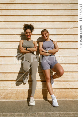 Smiling female sportswomen with crossed hands have a rest after morning jogging outdoors  112878051