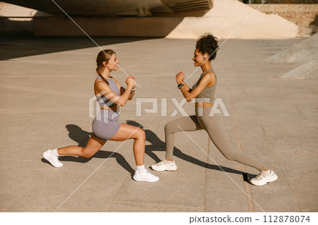 Athletic women in sportswear are stretching legs before doing workout outside in morning 112878074