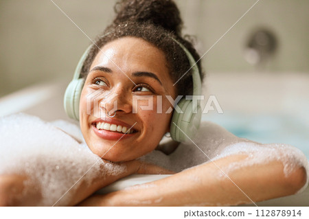 Woman, happy in a bathtub, smiling with black hair and headphones Woman, happy in a bathtub, smiling with black hair and headphones 112878914