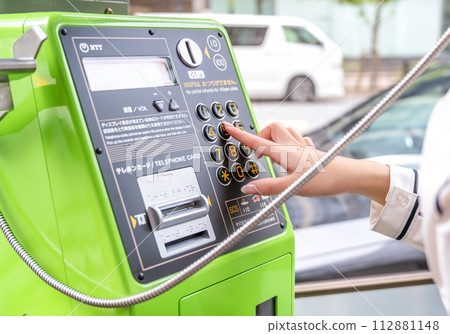Image cut of a young woman using a public phone due to mobile phone communication failure 112881148