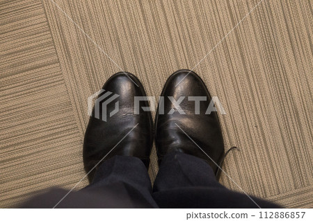 A man in elegant black shoes indoors. A man in elegant black shoes indoors. 112886857