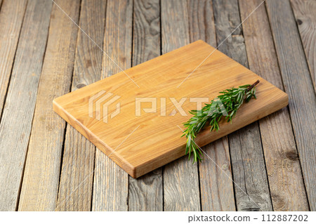Cutting board and rosemary on an old wooden table. Cutting board and rosemary on an old wooden table. 112887202
