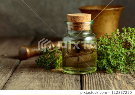 Bottle of thyme essential oil with fresh thyme twigs. 112887230