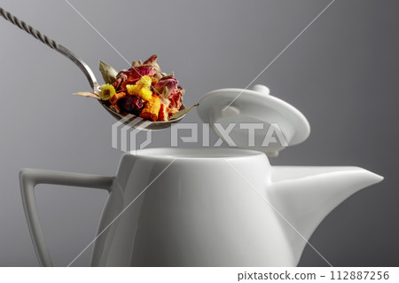 The mix of dried herbs and flowers is poured into the teapot. 112887256