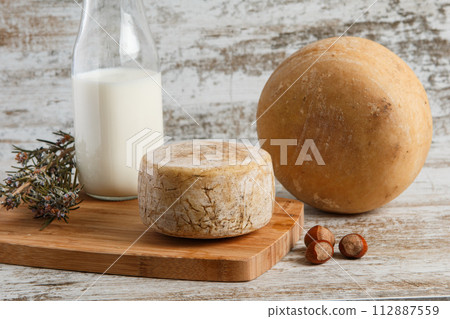 Artisanal and natural whole cheese, placed on a wooden board and without labels. 112887559