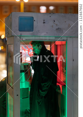 A man is talking on a phone in a booth A man is talking on a phone in a booth 112887602