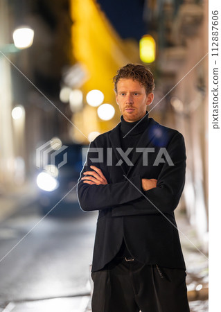 A handsome man is standing in the street with his arms crossed A handsome man is standing in the street with his arms crossed 112887606