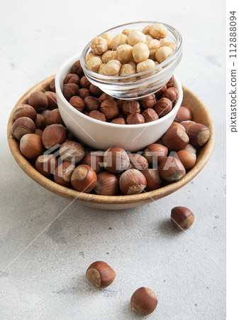 Bowls with peeled and whole healthy hazelnut nuts on light table. Bowls with peeled and whole healthy hazelnut nuts on light table. 112888094