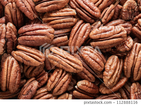 Raw peeled brown pecan nuts top view macro background. 112888116