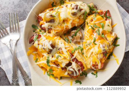 Chicken breasts are topped with a honey mustard sauce, bacon, cheese, and mushrooms closeup in the baking dish. Horizontal top view Chicken breasts are topped with a honey mustard sauce, bacon, cheese, and mushrooms closeup in the baking dish. Horizontal top view 112889932