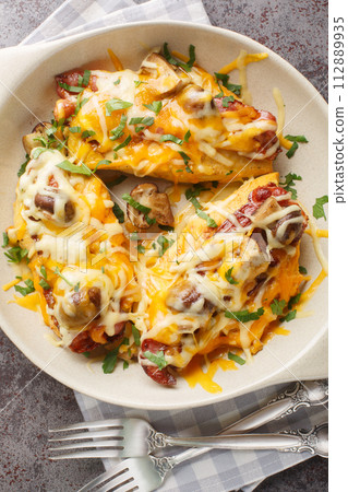 Baked chicken breasts with sauteed mushrooms, crispy bacon, melted cheddar and Monterey Jack cheese, honey mustard sauce closeup in the baking dish. Vertical top view Baked chicken breasts with sauteed mushrooms, crispy bacon, melted cheddar and Monterey Jack cheese, honey mustard sauce closeup in the baking dish. Vertical top view 112889935
