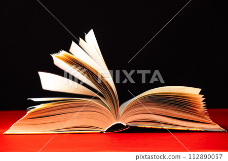 Pages of a thick book are turned on a red and black background. Pages of a thick book are turned on a red and black background. 112890057