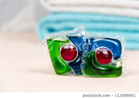 Laundry pods capsules on beige background with soft towels 112890061