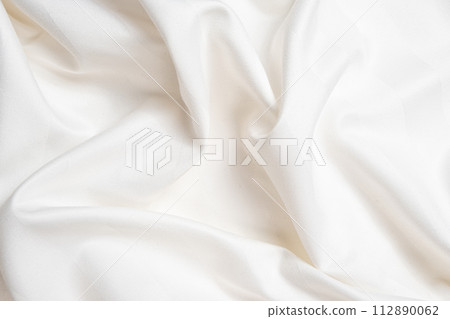 Waves and patterns of crumpled natural satin white milk color fabric. Waves and patterns of crumpled natural satin white milk color fabric. 112890062