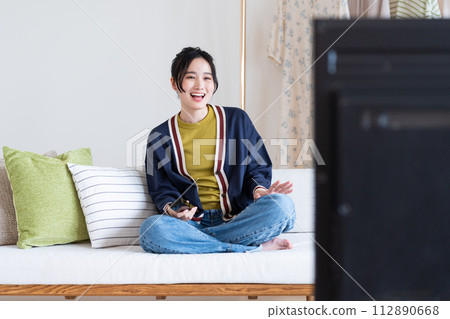 A young lady watching TV in the living room 112890668