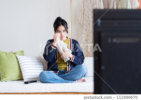 一位年輕的女士在客廳裡看電視 112890670