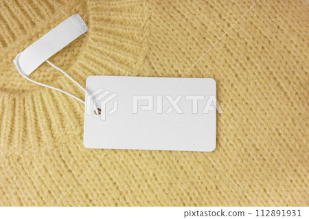Blank clothing tag and inner label on neck of yellow knitted sweater background 112891931