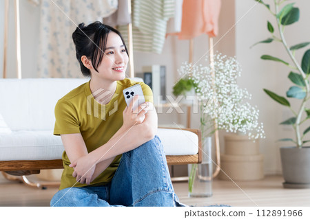 年輕女子在客廳看智慧型手機 年輕女子在客廳看智慧型手機 112891966