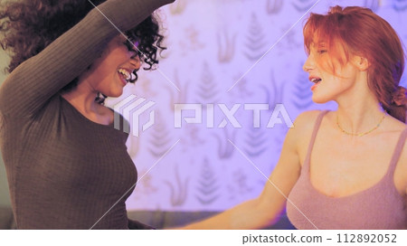 Women holding hands having fun dancing together in a party Women holding hands having fun dancing together in a party 112892052