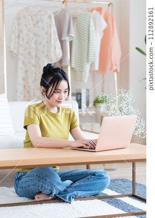 A young lady who plays a personal computer in the living room 112892161