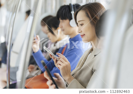 Profile of a business woman operating a smartphone on a train Profile of a business woman operating a smartphone on a train 112892463